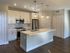 Modern kitchen with sleek white cabinetry, stainless steel appliances, and elegant pendant lighting over a spacious island.