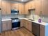 Elegant modern kitchen with warm wood cabinetry, stainless steel appliances, and sleek tile backsplash.
