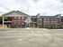 Charming red-brick apartment complex with well-maintained landscaping and ample parking space, showcasing classic architectural design and inviting curb appeal.