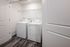 Modern laundry room with sleek white washer and dryer units, set against elegant hardwood flooring and minimalistic shelving.