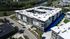 Modern apartment complex with stylish design, surrounded by lush greenery and conveniently located near a scenic river.