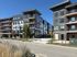 Modern, stylish apartment complex with multiple stories, large windows, and private balconies set in a vibrant neighborhood.