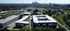 Panoramic aerial view of modern apartment complex surrounded by lush greenery, offering a serene lifestyle with city skyline in the background.
