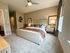 Contemporary bedroom with plush beige carpet, modern decor, and ample natural light from a large window.
