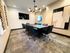 Modern conference room with a sleek wooden table, eight plush chairs, stylish lighting, and contemporary artwork.
