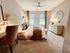 Inviting bedroom with elegant d&eacute;cor, featuring a plush bed, cozy seating area, and bright windows, designed for relaxation and comfort.