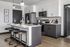 Contemporary kitchen with sleek black and white cabinetry, modern appliances, and elegant pendant lighting above a stylish breakfast bar with chic stools.