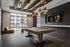 Modern game room with a sleek pool table, stylish lighting fixtures, and expansive windows offering natural light.