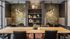 Chic communal space featuring stylish booths, vibrant botanical wallpaper, golden pendant lighting, and elegant decor.