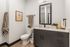 Contemporary bathroom with sleek dark vanity, elegant decor, and warm wood flooring. Features modern mirror and stylish accents.