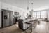 Modern open-concept kitchen and living area with chic pendant lighting, sleek stainless steel appliances, and a cozy seating nook by large windows.