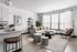 Modern living room with large windows streaming natural light through.  The open-concept design includes a kitchen with a chic island and contemporary seating.