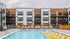 Modern apartment building with stylish wood accents featuring a luxurious outdoor pool and sun loungers, perfect for relaxation and leisure.