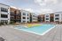 Modern apartment community with a luxurious outdoor swimming pool featuring yellow loungers, surrounded by sleek landscaping and contemporary architecture.