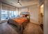 Bright and inviting bedroom with elegant decor, featuring a cozy bed with plush pillows, modern ceiling fan, and large window offering city views.