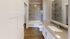 Elegant bathroom with a modern vanity, spacious bathtub, and stylish tile walls, offering a luxurious retreat.