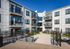 Contemporary apartment community featuring modern balconies, sleek architecture, and a welcoming courtyard under a bright blue sky.