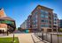 Modern apartment community with brick facade and large windows, situated along a vibrant walkway in Fishers, perfect for urban living.