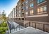 Contemporary multi-story apartment community with modern brick facade, large windows, and inviting landscaped pathway leading to the entrance.