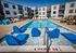 Luxurious outdoor pool area with modern sun loungers and inviting water features, surrounded by stylish apartment buildings.