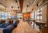 Chic clubhouse lounge with modern industrial design, stylish tables, and bright floor-to-ceiling windows.