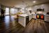 Modern open-plan kitchen and living room with sleek stainless steel appliances, elegant pendant lighting, and cozy seating area with warm wood flooring.