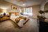 Elegant bedroom with natural light from large windows, perfect for relaxation.