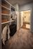Elegant walk-in closet with plush carpeting, showcasing built-in shelving and modern open hanging space leading into a stylish bathroom.