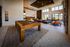Luxurious modern lounge with a sleek billiards table, stylish seating, and floor-to-ceiling windows offering scenic views.