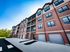 Modern apartment building with stylish red brick facade, large windows, and private balconies.
