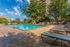 Inviting outdoor pool area with stylish lounge chairs, surrounded by lush greenery and modern high-rise backdrop.