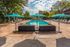 Inviting outdoor pool area with turquoise umbrellas, chic lounge chairs, and vibrant greenery, perfect for relaxation and sunny city views.