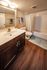 Elegant bathroom featuring a modern vanity with ample storage, sleek fixtures, and a relaxing bathtub surrounded by tasteful tilework.