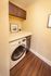 Chic laundry nook featuring a modern washer/dryer combo, elegant dark cabinetry, and sleek wood flooring.