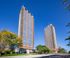 Majestic high-rise apartments under a clear blue sky, surrounded by lush greenery and vibrant urban living.