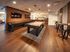 Elegant recreation room with sleek wood flooring, featuring a modern pool table and shuffleboard, complemented by stylish seating and ambient lighting.