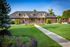 Charming brick building with welcoming office entrance, surrounded by vibrant landscaping and lush green lawns.