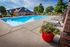 Charming outdoor swimming pool with elegant lounge chairs, vibrant floral arrangements, and scenic greenery, perfect for relaxation and leisure.