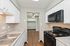 Chic kitchen with modern black appliances, elegant granite countertops, and crisp white cabinetry, leading to a spacious laundry area with hardwood flooring and a ceiling fan.