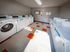 Bright and spacious laundry room featuring modern washing machines and dryers with vibrant orange accents for a welcoming atmosphere.
