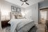Inviting bedroom with elegant contemporary decor, featuring a plush bed, stylish nightstands, modern ceiling fan, and artful wall paintings.