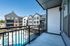 Modern apartment balcony view overlooking a pristine swimming pool and stylish residential buildings under clear blue skies.