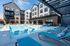 Chic modern apartment building with a beautiful sunlit pool area, featuring stylish lounge chairs and vibrant decor.