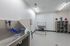 Modern and spacious pet grooming room with a sleek stainless steel sink, colorful pet artwork, and organized shelving.