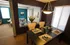 Elegant dining area with a sleek black table set for four, overlooking a cozy living room with stylish decor and vibrant accents.
