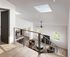 Modern loft apartment showcasing a bright open living area with skylight, elegant staircase, and cozy seating, exuding contemporary charm.