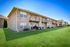 Charming apartment community exterior with beautiful green lawn, private balconies, and a welcoming ambiance.