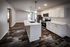 Modern kitchen with sleek white cabinetry, stainless steel appliances, and elegant pendant lighting over a spacious island. Rich wood flooring enhances the open, inviting space.