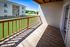Sunlit balcony with wooden railing offering serene views of vibrant green lawns and modern apartment community.