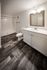 Modern bathroom with elegant wood flooring, sleek white vanity, and spacious walk-in shower.